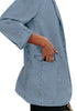 Closeup view of model wearing light blue lapel collar flap pockets open-front denim blazer