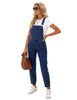 Model poses wearing dark blue cuffed denim bib jeans overalls