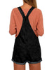 Back view of model wearing black rolled hem shorts denim bib overall