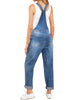 Back view of model wearing light blue cuffed hem ripped bib denim overall jumpsuit