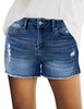 Model is wearing dark blue mid-waist raw hem distressed faded denim shorts