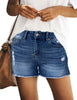 Posing model wearing dark blue mid-waist raw hem distressed faded denim shorts