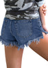 Back view of model wearing medium blue frayed raw hem distressed denim shorts