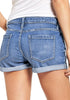 Back view of model in light blue roll-over hem button-up distressed denim shorts