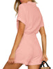 Back view of model wearing blush pink short sleeves button-down belted romper
