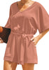 Angled shot of model wearing blush V-neckline keyhole-back loose belted romper