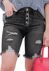 Front view of model wearing black frayed hem ripped button-up denim bermuda shorts