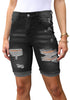 Front view of model wearing black plus size mid-waist ripped denim bermuda shorts.