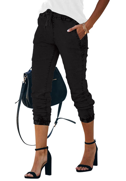 Closeup shot of model wearing black elastic-waist welt pockets denim jogger pants