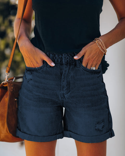 Model wearing dark blue high-waist roll-over distressed jean shorts