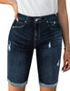 Front view of model wearing dark blue mid-waist raw hem distressed denim bermuda shorts
