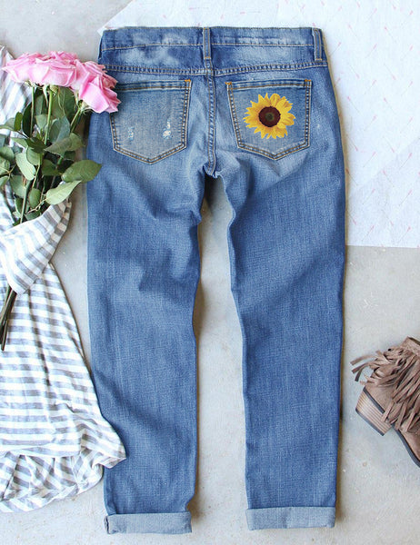 Back view of blue sunflower-print patch ripped rolled hem denim boyfriend jeans