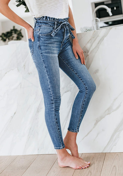 Model poses wearing blue high-waist acid wash belted denim skinny jeans