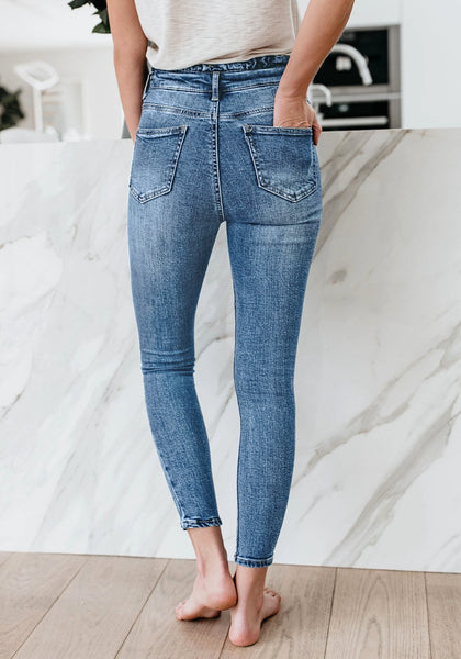 Back view of model wearing blue high-waist acid wash belted denim skinny jeans