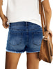 Back view of model wearing dark blue mid-waist raw hem distressed faded denim shorts