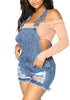 Angled shot of model in blue denim ripped shorts bib overall