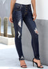 Angled shot of model wearing dark blue high-rise ripped buttoned denim jeans
