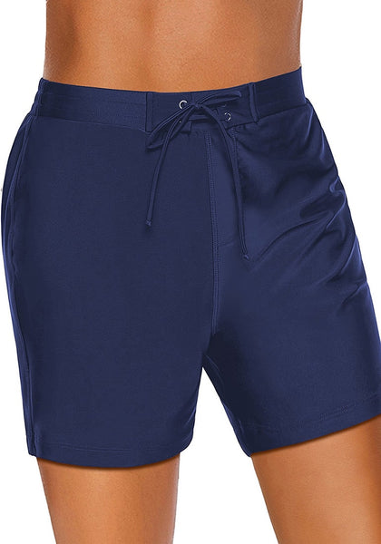 Angled shot of model wearing navy lace-up board shorts