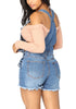 Back view of model wearing blue denim ripped shorts bib overall