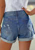 Back view of model wearing blue roll-over distressed denim shorts