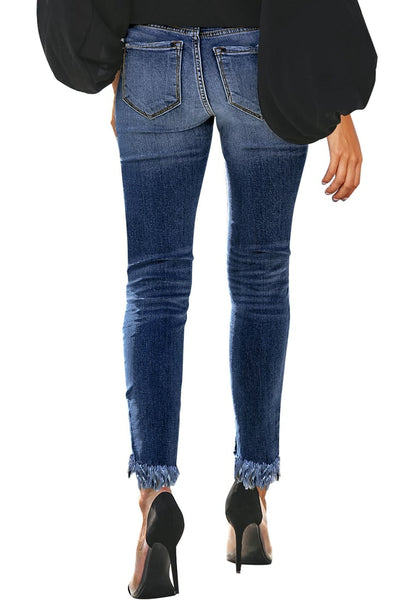 Back view of model wearing dark blue mid-waist raw hem  cropped ripped denim jeans