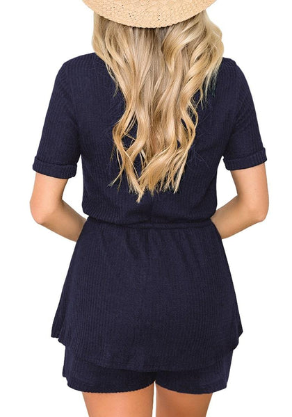 Back view of model wearing navy crew neck overlay drawstring knit romper