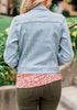 Back view of model wearing light blue button down women's denim jacket