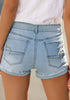 Back view of model wearing light blue frayed roll-hem ripped denim shorts