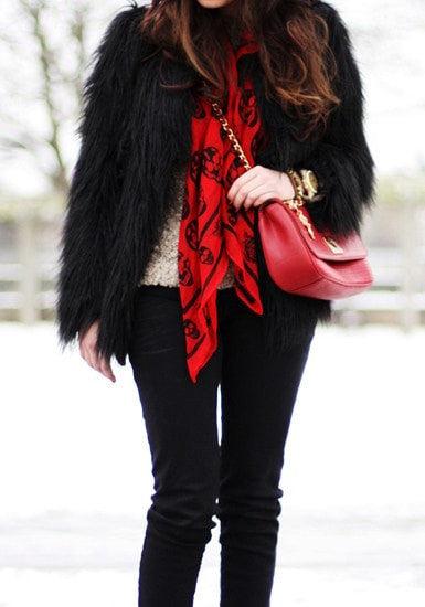 Front view of model in black faux fur coat with red scarf