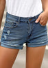 Front view of model wearing blue frayed roll-hem ripped denim shorts