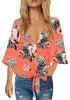 Front view of model wearing coral V-neckline button-up tie-front floral top