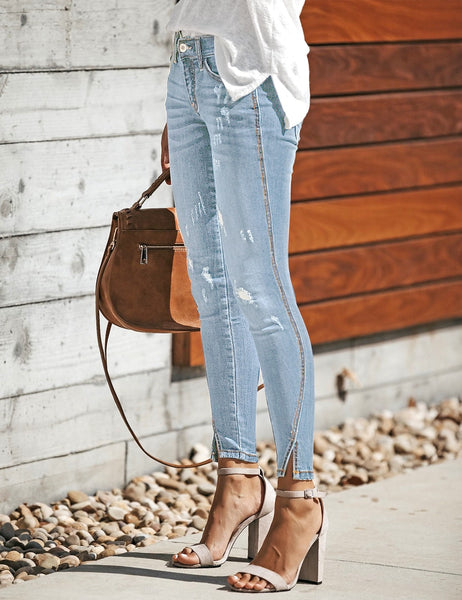 Side view of model wearing light blue split-hem ripped skinny denim jeans