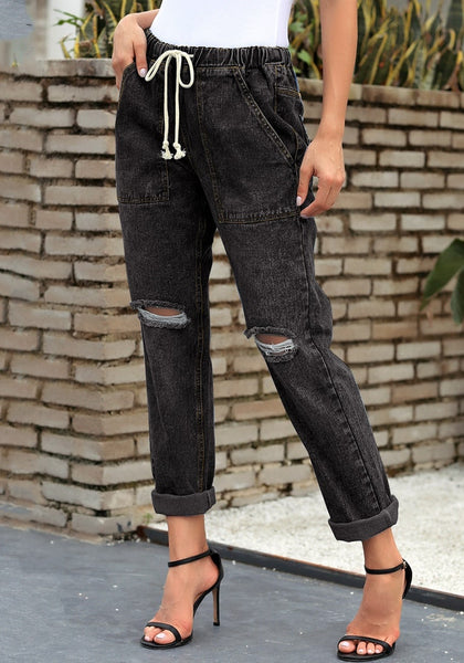 Model poses wearing black drawstring-waist cuffed ripped boyfriend jeans