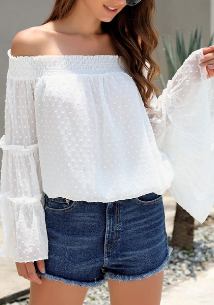 Model poses wearing white bell sleeves dotted loose off-shoulder top