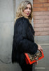 Right side shot of model in black faux fur coat with bag