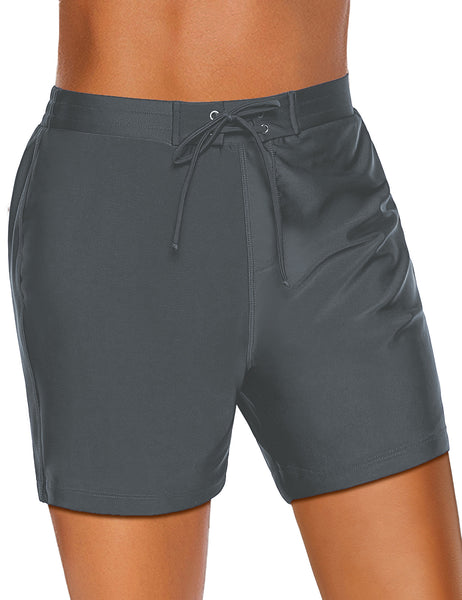 Angled view of model wearing dark grey lace-up board shorts