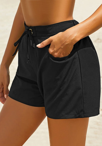 Side view of model wearing black elastic-waist side pockets lace-up board shorts